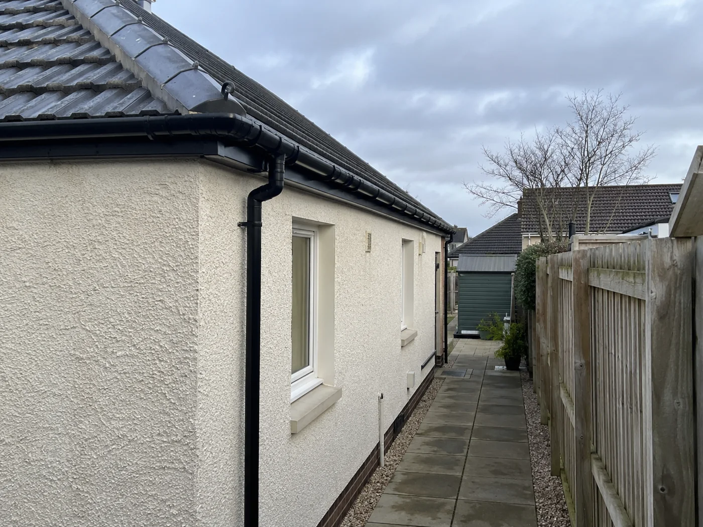 Paved side path beside a house with roof eaves above